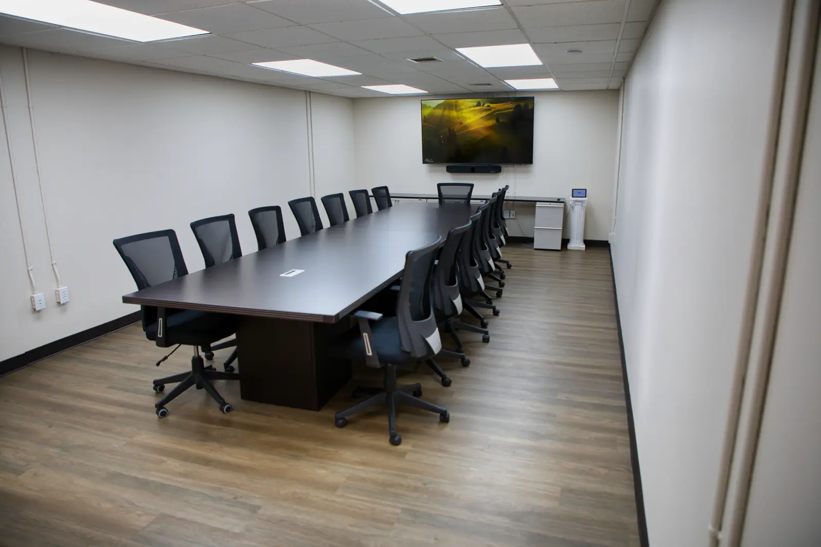 Conference Room angled view of the table and chairs with the wall display and credenza