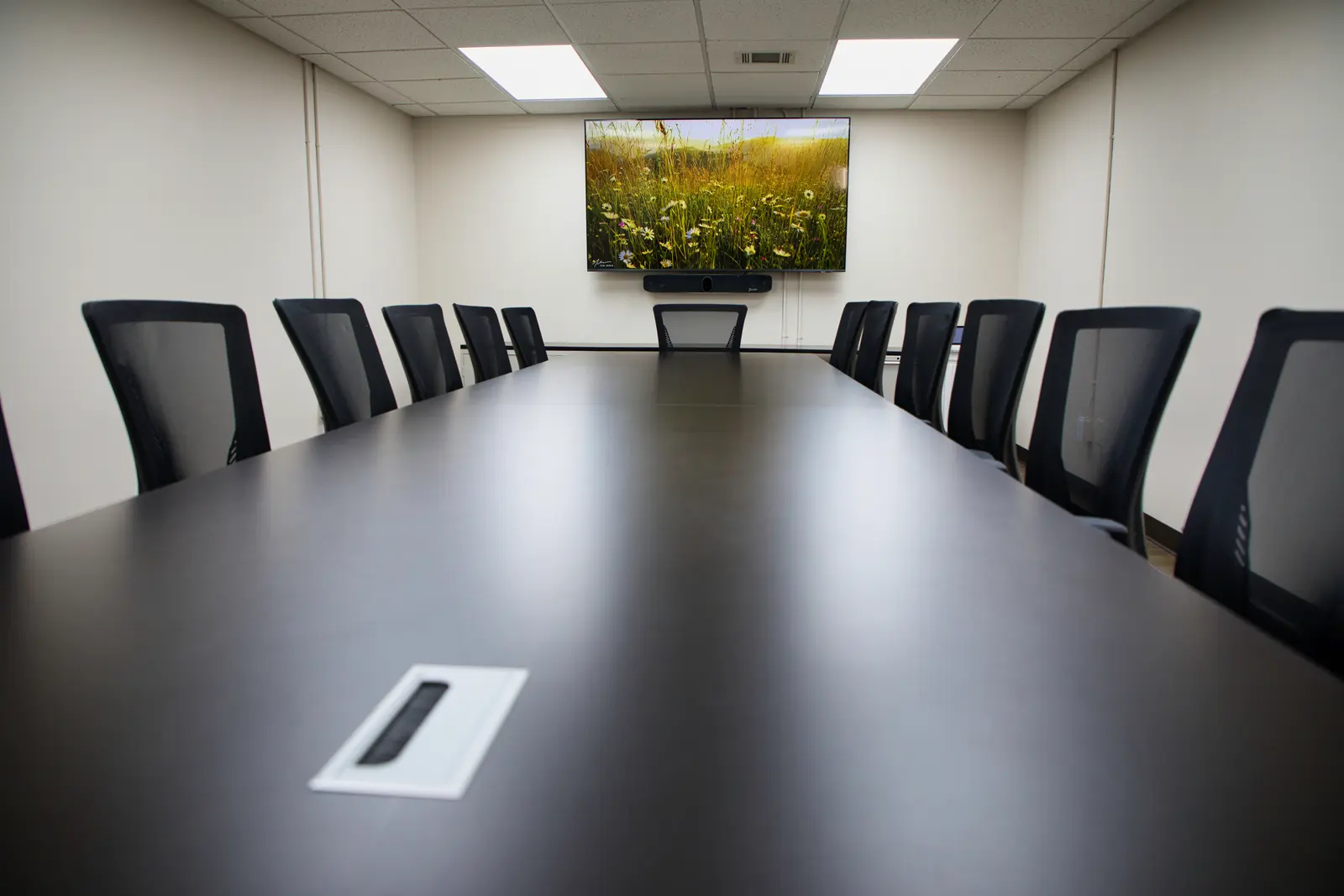 Low, dramatic angle down the Conference Room tabletop toward the wall display